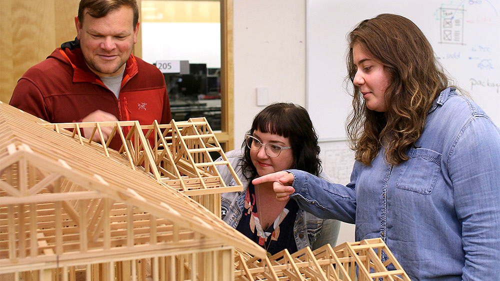 Students working on a wooden architectural model together