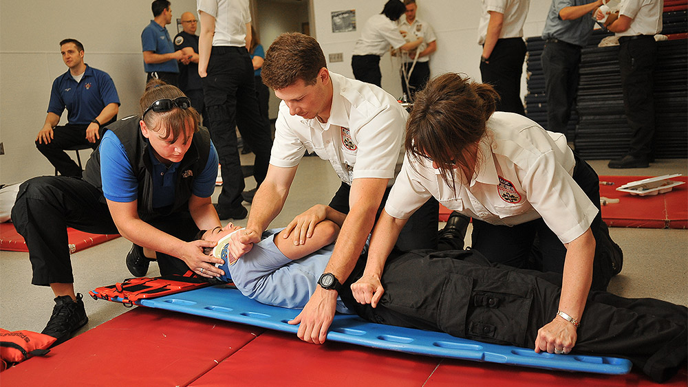 Students in a training simulation with another student acting with a spinal injury