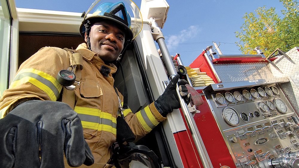 Student in a firefighter uniform climbing out of a fire truck