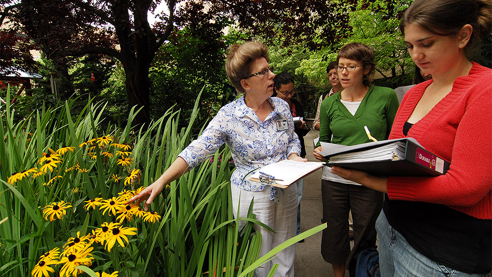 Gerontology instructor leading students through the horticulture therapy garden