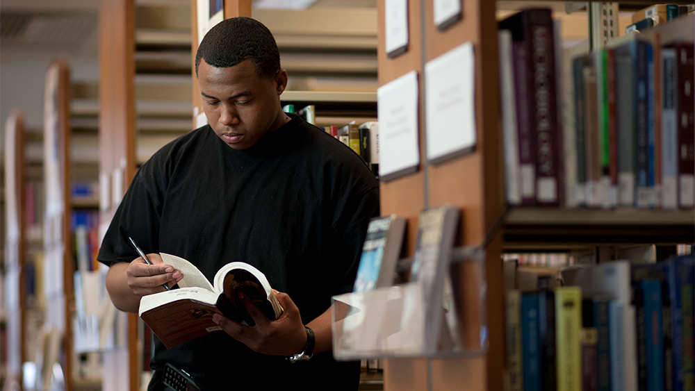Student looking at a book in the library