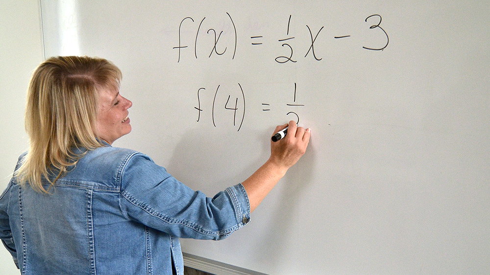 Math instructor writing equations on a whiteboard