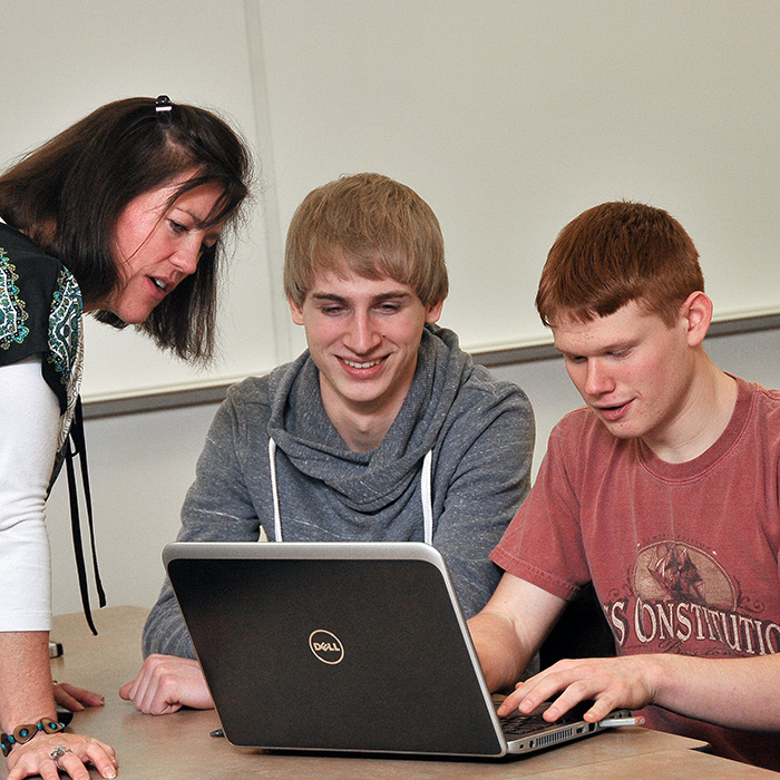 Students working together at a computer with an instructor