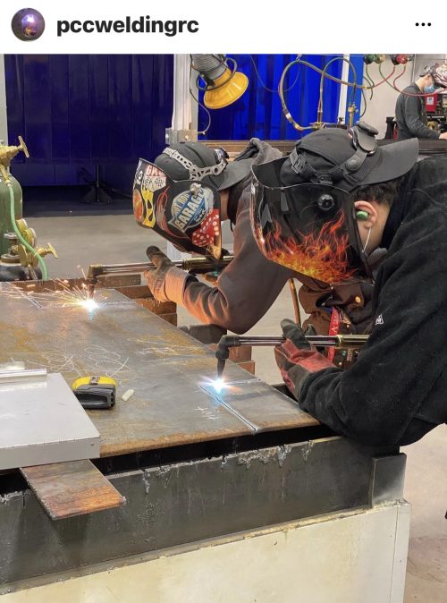 Two students welding side by side