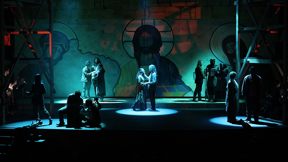 Dark stage with spotlights on groups of actors