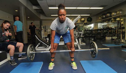 Student lifting weights in a campus fitness and weight room